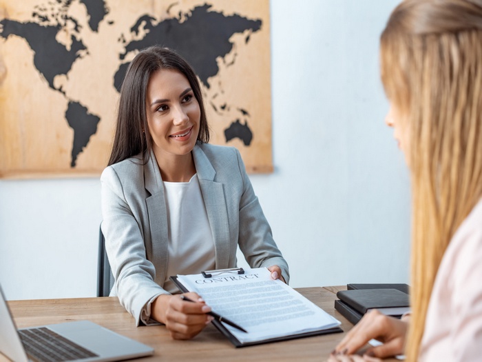 smiling travel agent showing signature place in contract to client